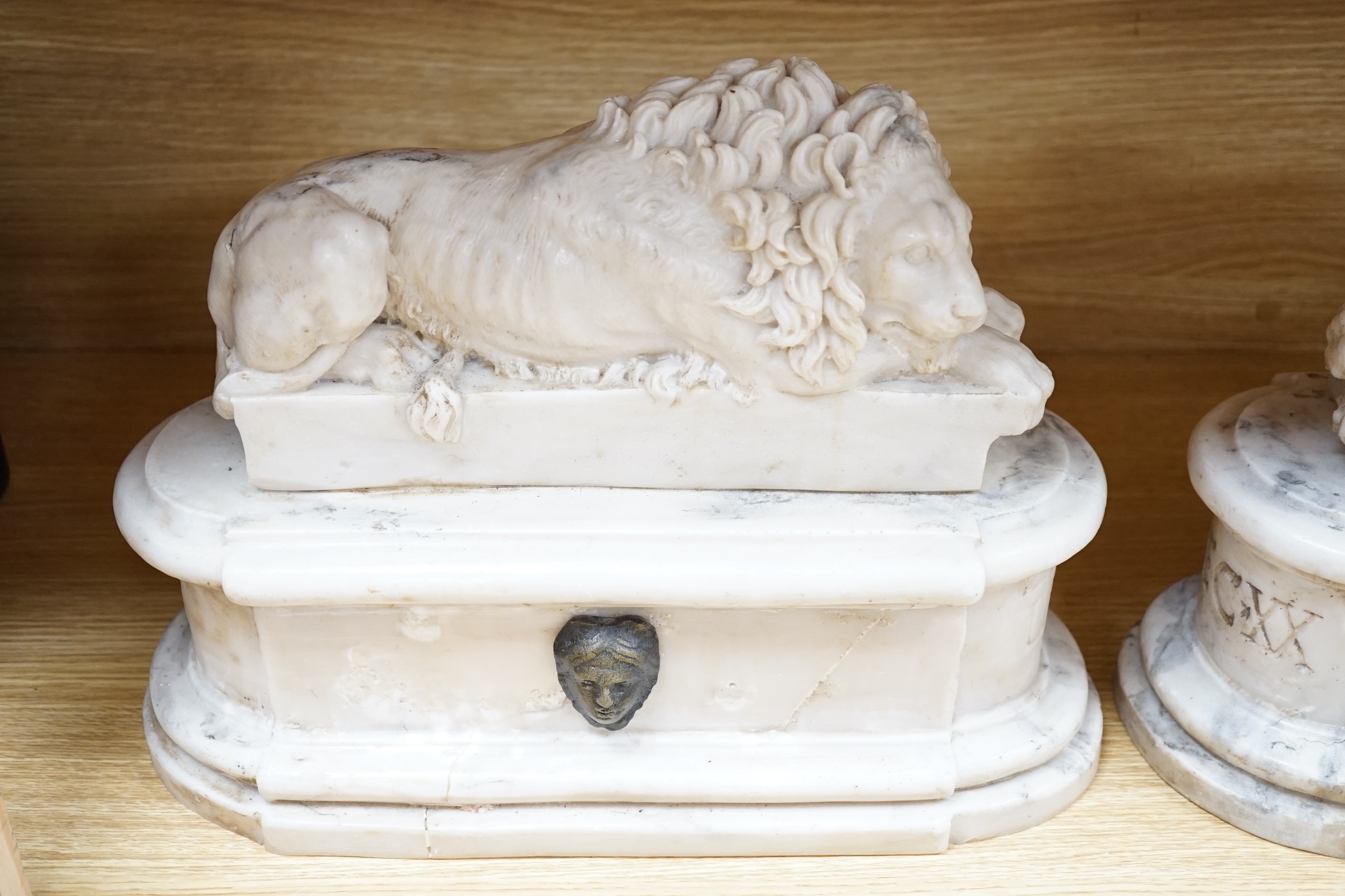 After the Antique. A pair of marble resin models of the Medici lions, each seated upon an oblong plinth, applied with bronze masks, inscribed LECXX, 41cm long, 15cm deep, 29cm high